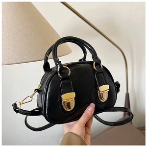 Detail of black mini Boston bag with glossy PU leather and dual gold buckle accents