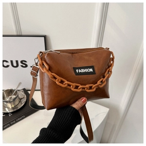Detail of brown PU leather crossbody bag featuring a stylish orange acrylic chain and logo