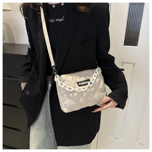 Dettaglio della borsa tote beige trapuntata con etichetta FASHION e catena decorativa bianca