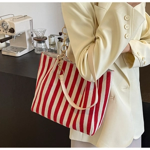Detail der rot-weiß gestreiften Shopper-Tasche mit Goldkette und Lederriemen am Model