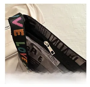 Détail de la fermeture éclair argentée d'un sac avec bandoulière tissée LOVE colorée