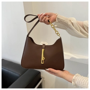 Detail of dark brown retro shoulder bag featuring a vintage gold metal lock and chain strap