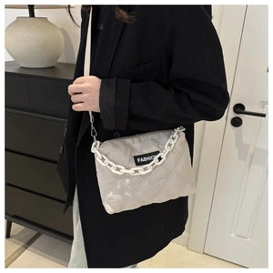 Dettaglio della borsa shopper beige trapuntata con catena in plastica bianca e etichetta