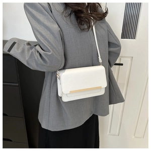 Detail showing white crocodile pattern leather crossbody bag with gold metal trim accent