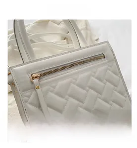 Detailed macro view of white quilted faux leather handbag with premium golden hardware zippers