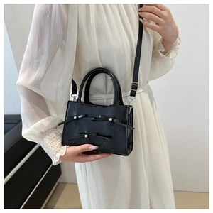 Dettaglio della borsa nera in pelle PU con fiocchi decorati con perle e manico superiore