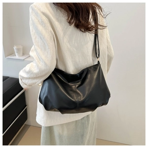 Close-up of black leather hobo tote bag showing soft drape and vertical stitching detail