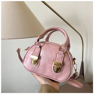 Close-up of pink oil wax leather Boston bag with decorative gold metal buckles and handles