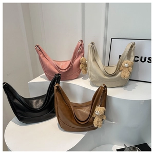 Detail view of four vintage leather crescent bags in multiple colors with bear charms