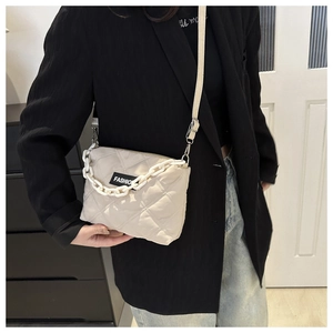 Dettaglio borsa a tracolla trapuntata beige con catena bianca e etichetta FASHION