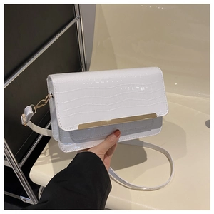 Detail of white crocodile pattern crossbody bag with sleek gold metal trim on the flap