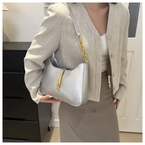 Silver crescent shoulder bag featuring a metallic texture and iconic gold piston lock