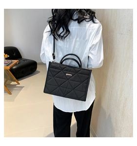 Black quilted tote bag shown on model featuring diamond stitching and metal logo detail