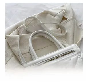Close-up of white quilted handbag with woven texture and gold zipper on tweed blazer