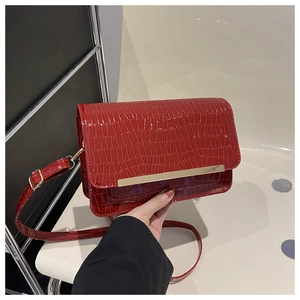 Macro shot of red faux crocodile leather texture and golden metal bar on the handbag