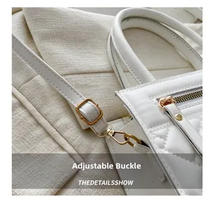Close-up of golden adjustable buckle and hardware on white quilted shoulder bag