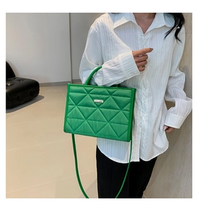 Detail of green quilted handbag with geometric texture and silver metallic plaque