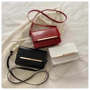 Detailed view of red black and white croc-embossed crossbody bags with gold hardware