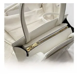 Macro view of smooth golden zipper and refined texture on the white handbag