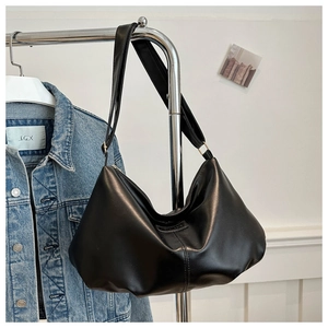 Detail of black faux leather crescent tote bag with pleated design and wide shoulder strap