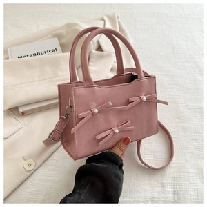 Dettaglio della borsa rosa in pelle PU con fiocchi decorativi e applicazioni di perle