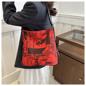 Détail du sac fourre-tout rouge avec imprimés graffiti porté sur un blazer noir