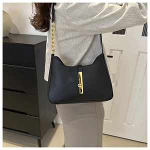 Detail view of the black leather shoulder bag with gold hardware and chain strap