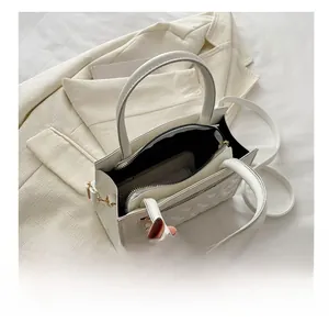 Top view of white crossbody bag interior featuring two compartments and a zipper pocket