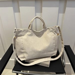 Minimalist beige corduroy tote bag with adjustable strap on a chair for daily commute