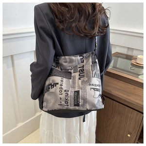 Sac fourre-tout tendance avec imprimé journal porté par un mannequin dans un décor sobre