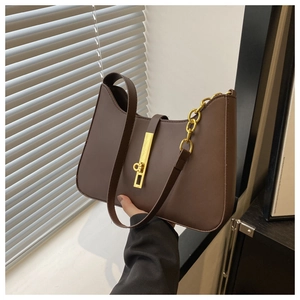 Detail of vintage brown leather underarm bag with gold metal twist lock and chain strap