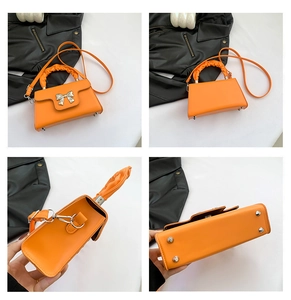 Detail view of orange crossbody bag with metal bow accent and protective base studs