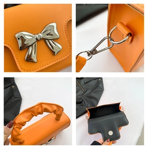 Close-up of orange handbag showing silver bow hardware and cloud-pleated handle detail