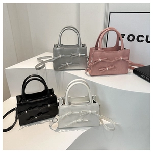 Quattro eleganti borse con fiocchi e perle mostrate nei colori argento, rosa, nero e bianco