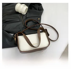 Detail der weißen Handtasche mit Litschi-Muster, braunen Riemen und Gold-Logo