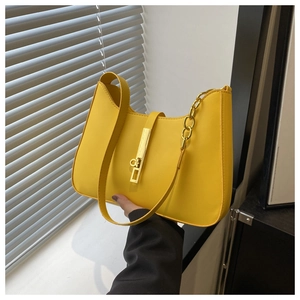 Detail of a bright yellow leather underarm bag with a golden metal buckle and chain strap