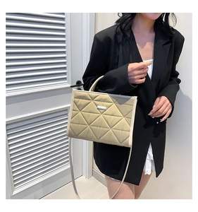 Detail of olive green quilted handbag featuring silver metal plate and dual handles