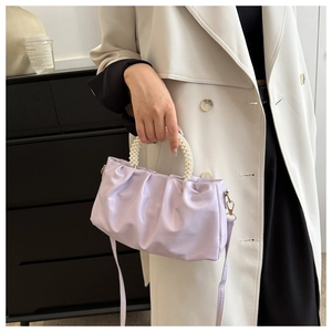 Detail of light purple pleated cloud bag with elegant pearl handle and slim strap