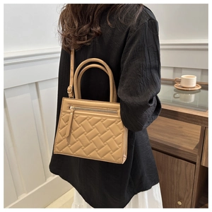 Close-up of khaki quilted texture and front zipper pocket on a stylish women handbag