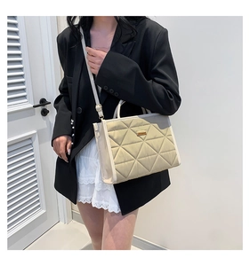 Model showing beige quilted crossbody bag with adjustable strap and metal hardware