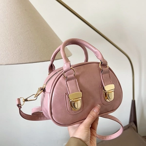 Pink oil wax leather Boston bag with gold hardware shown as a handheld crossbody purse