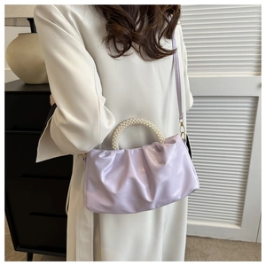 Detail of lavender cloud bag featuring pleat design and elegant pearl beaded handle