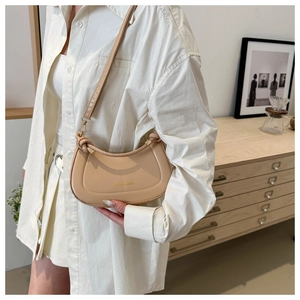 Detail of minimalist beige half-moon shoulder bag with side knot and logo print