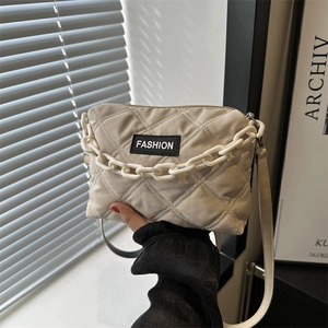 Borsa tote beige trapuntata a rombi con etichetta fashion e catena bianca decorativa