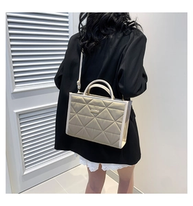 Quilted tote bag with diamond pattern shown on model in a minimalist indoor setting