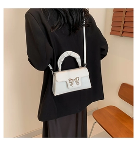 Close-up of white PU leather crossbody bag with silver bow ornament and ruffled handle