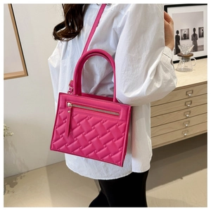 Model wearing a rose red quilted handbag with square pattern and adjustable strap