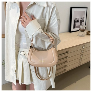 Detail of beige half-moon bag featuring a knotted handle and sleek fashion text