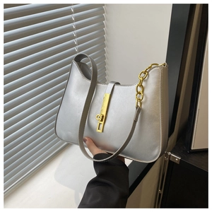 Close-up of metallic silver shoulder bag featuring a gold bar lock and chain detail
