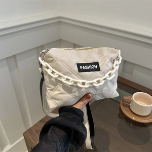 Borsa tote beige trapuntata con catena decorativa e etichetta alla moda